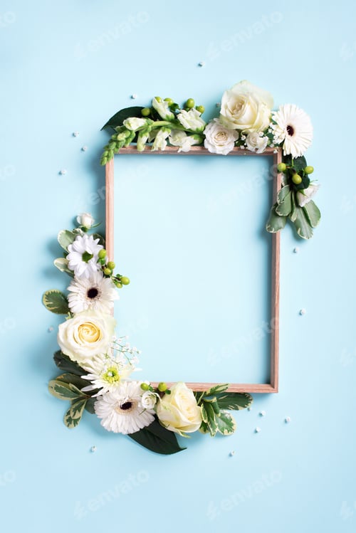 Preview: Floral frame of white flowers, green leaves on blue paper background. Flat lay, top view. Spring and
