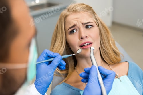 Preview: cropped shot of dentist examining teeth of frightened female client