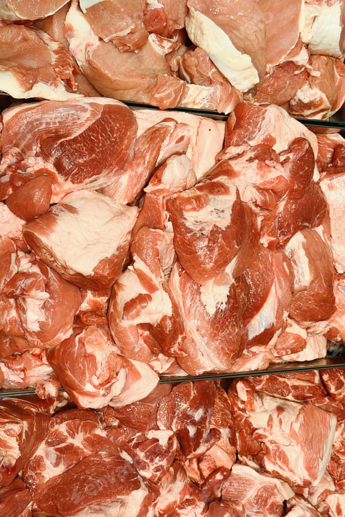Preview: Various fresh raw pork meat cuts piled up and openly displayed for sale in a grocery store or market
