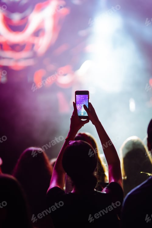 Preview: Hand with a phone records live music festival. People taking photographs with smart phone.