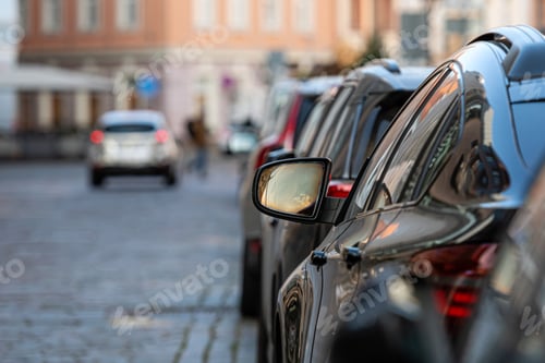 Preview: rows of different cars parked along the roadside in crowded city