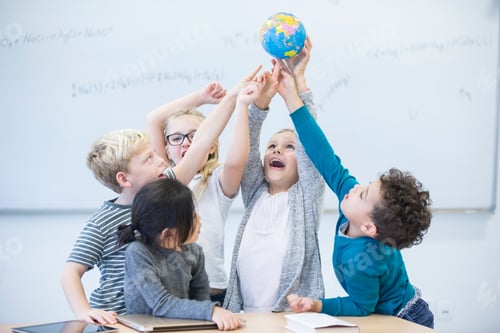 Preview: Happy pupils holding globe together in class