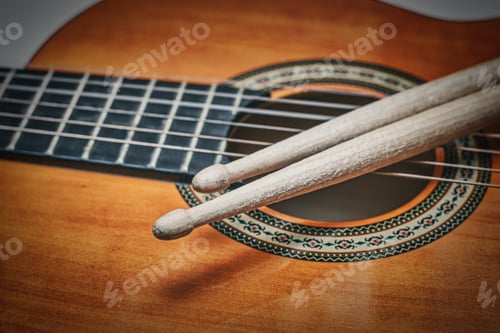 Preview: Detail of drumsticks on acoustic guitar
