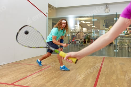 Preview: Couple holding squash racquets playing game match at sport club
