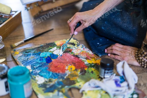 Preview: Close up of a woman making colors on a pallete.