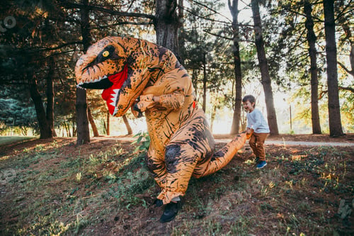 Preview: Father and son playing at the park, with a dinosaur costume, having fun with the family outdoor