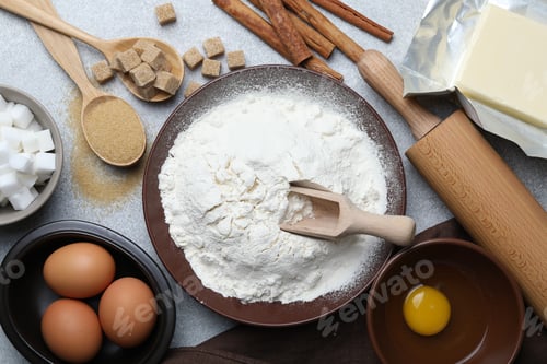 Preview: Rolling pin and ingredients for dough on light grey table, flat lay