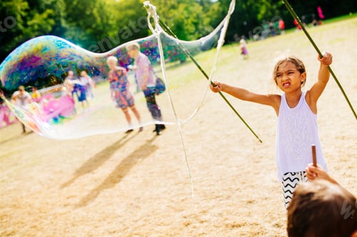 Preview: Girl (6-7) making soap bubbles at festival