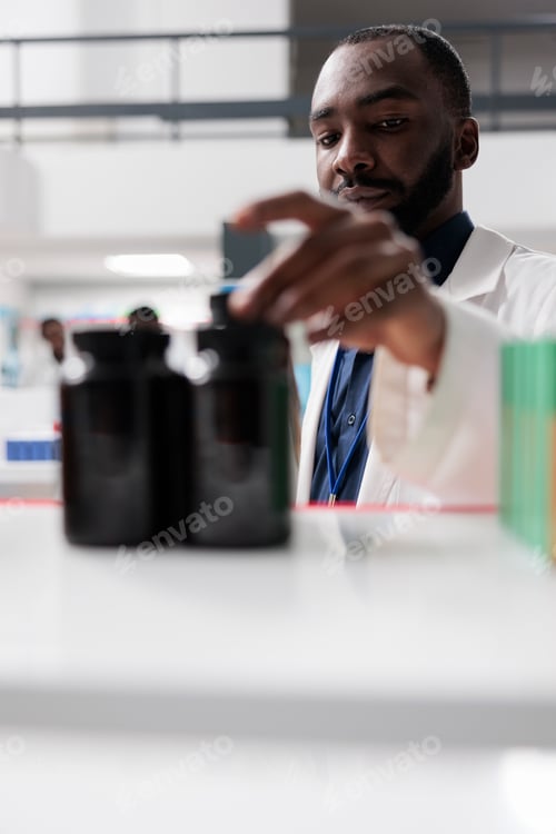 Preview: African american pharmacist taking medication bottles from drugstore shelf