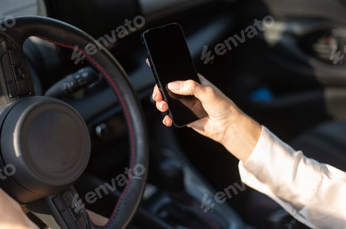 Preview: Driver holding smartphone in car