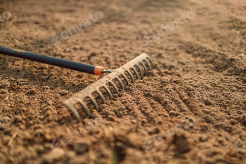 Preview: Close up of an new metal garden rake cleaning earth at spring time. Seasonal work