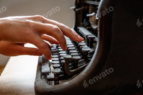 Preview: woman hands type on an old vintage dust-covered typewriter
