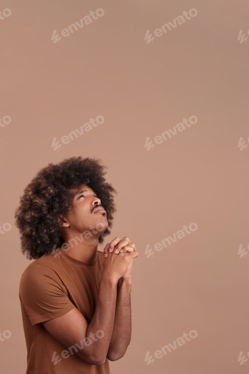 Preview: African man looking up while praying with folded hands