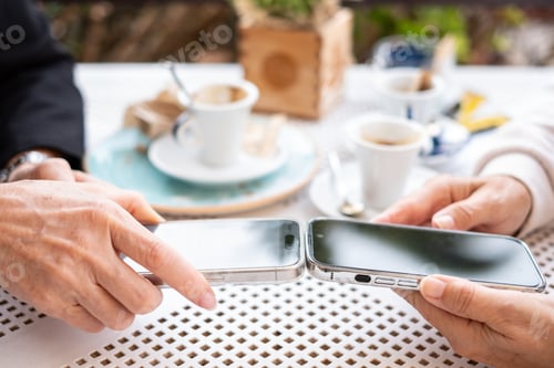 Preview: Close up view of two modern women's hands using apps and wireless technology to share files