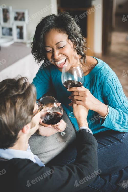 Preview: Young handsome mixed race couple in their house having a glass of red wine