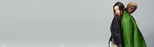 Preview: trendy interracial couple looking at camera while leaning on each other isolated on grey, banner