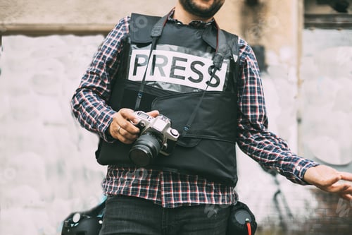Preview: Photojournalist with bulletproof vest holding his camera