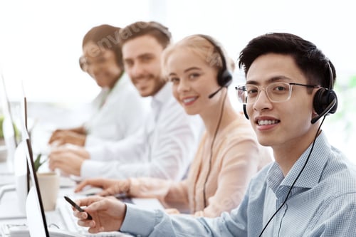 Preview: Smiling call center workers sitting in row near their computers at light office, blank space