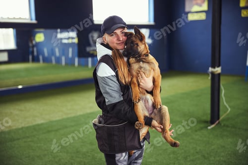 Preview: Pleased female trainer holding an adorable puppy