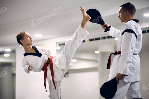 Preview: Martial artis with disability exercising high leg kick with her coach during taekwondo training.