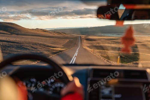 Preview: Man driving a car through wilderness on asphalt road in the sunset