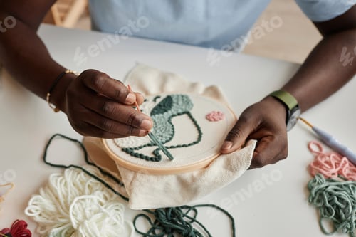 Preview: Hands of young African American male designer creating embroidery for clothes