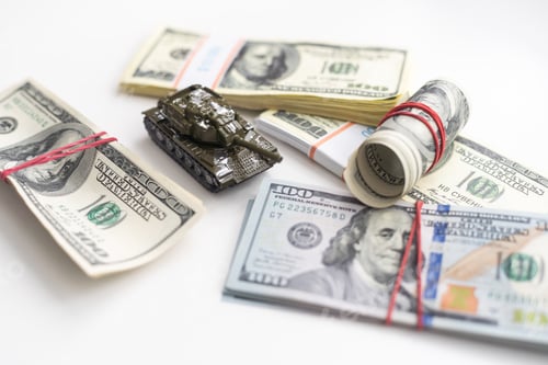 Preview: Toy tank on US hundred dollar bills banknotes close up. The concept of war costs, military spending
