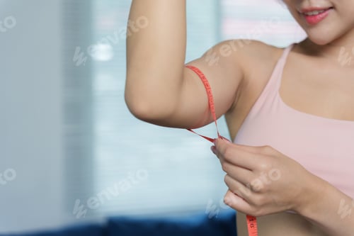 Preview: Woman measuring arm, focusing on fitness progress