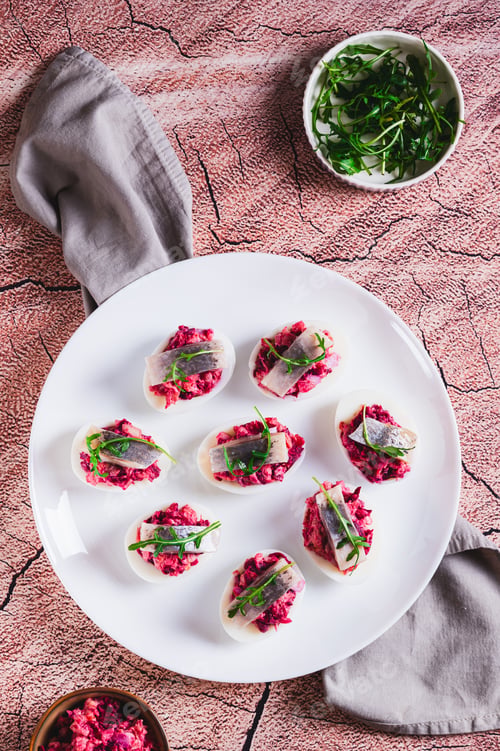 Preview: Eggs delived with vegetable salad, a piece of herring and arugula on a plate top and vertical view
