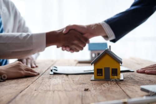 Preview: Business Handshake with Miniature House on Table