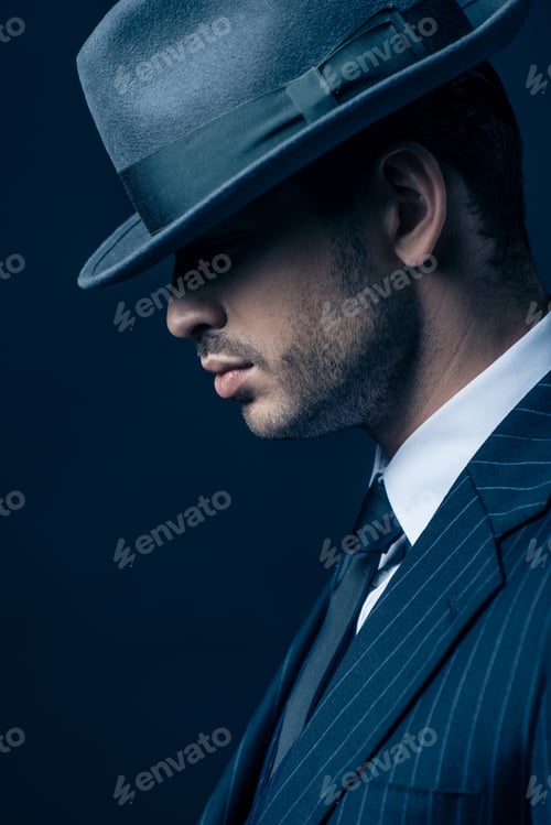 Preview: Profile of mafioso in suit and felt hat on dark background