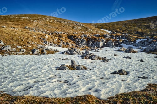 Preview: mountain and hill landscape with a snow field on a mountain - stones, rocks, grass, blue sky