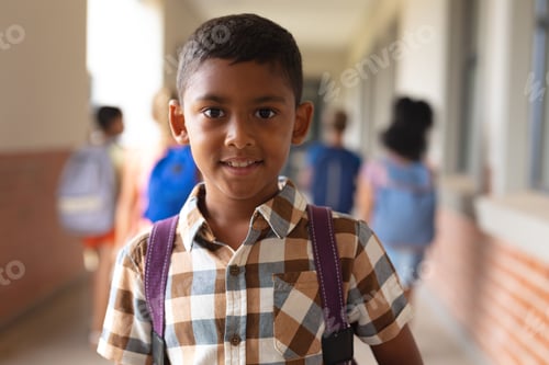 Preview: Portrait of smiling biracial elementary schoolboy standing in corridor