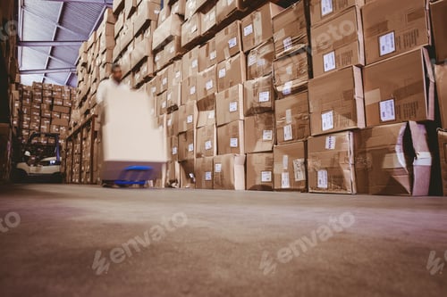 Preview: Blurred worker with fork pallet truck stacker with boxes in warehouse