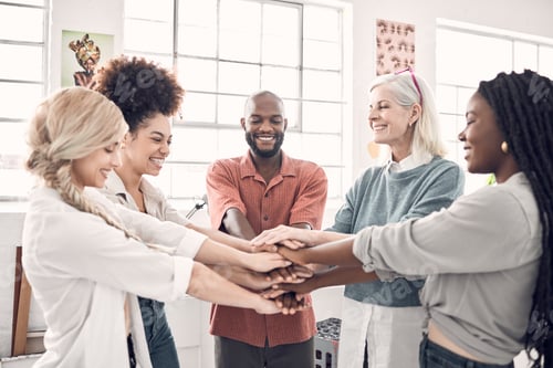 Preview: Group of five cheerful diverse businesspeople piling their hands together in an office at work. Hap