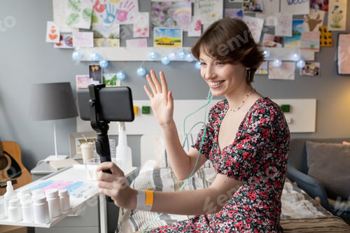 Preview: Happy young brunette female waving hand and looking in smartphone camera