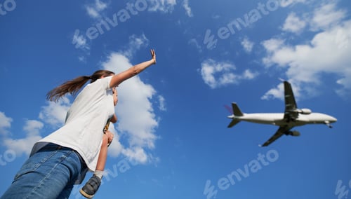 Preview: Woman with child waving hand to landing commercial airplane