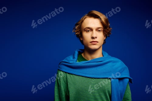 Preview: Young man exudes charm and confidence in vibrant fashion against a striking blue background