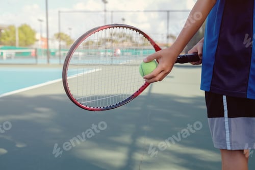 Preview: Young boy tennis player on outdoor blue court