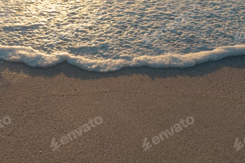 Preview: High angle view of wave foam on shore sand at beach during sunset