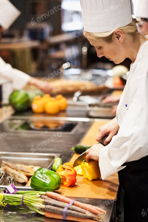 Preview: A caucasian female chef works cutting vegetables in a commercial kitchen,
