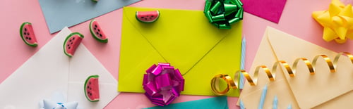 Preview: Top view of candies and gift bows on colorful envelopes on pink background, banner