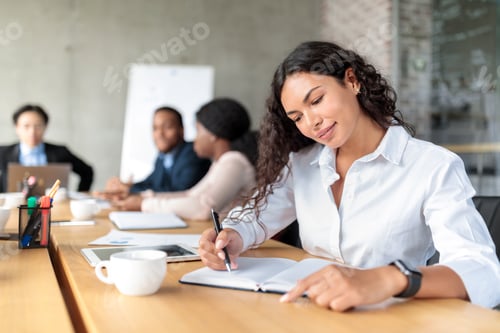 Preview: Businesswoman Writing In Notebook Sitting At Conference Meeting In Office