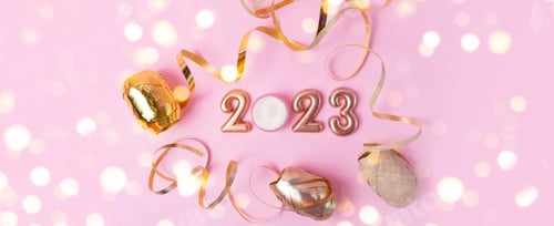 Preview: Top view of rose gold numbers 2023 on pink background.