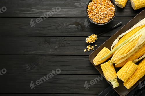 Preview: Tasty fresh corn cobs and kernels on black wooden table, flat lay. Space for text
