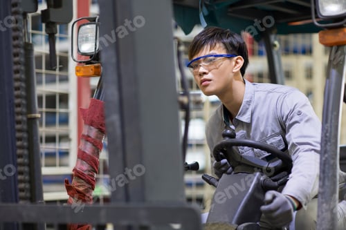Preview: Young Chinese workman driving forklift in the factory
