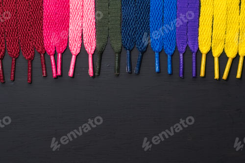 Preview: background of colored shoelaces on black wood, arranged vertically, concept of perfection