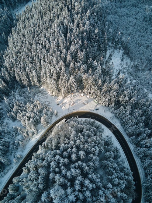 Preview: Aerial view of winter landscape with snow covered mountain hills and winding forest road in morning.