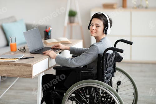 Preview: Teen with headphones works at home on laptop