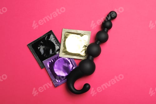 Preview: Anal ball beads and condoms on pink background, top view. Sex game